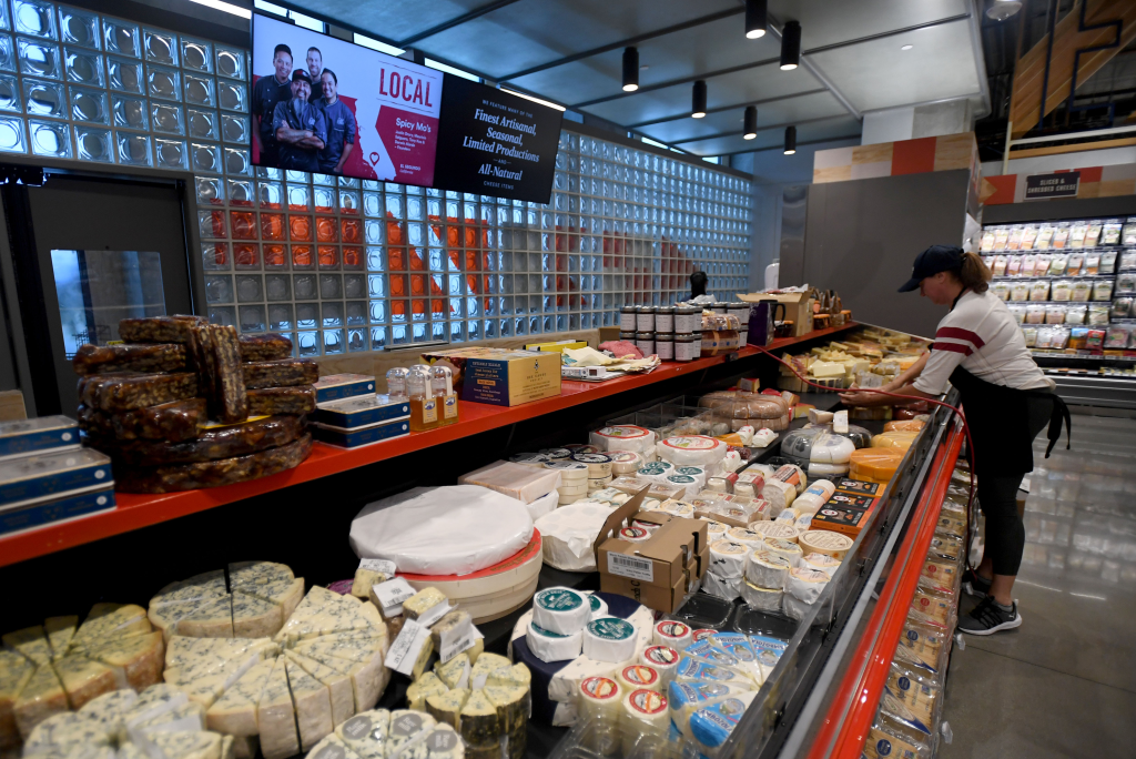 A Whole Foods Market employee stocking cheese in the cheese section.