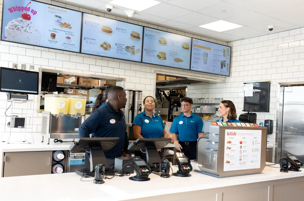 Four Chick-fil-A employees stand behind the counter at a new restaurant location.