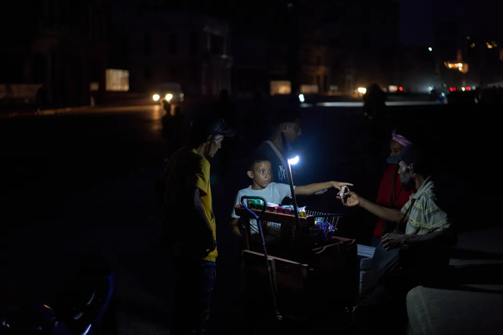 A child pays a vendor at a market stall during a blackout in Havana, Cuba.
