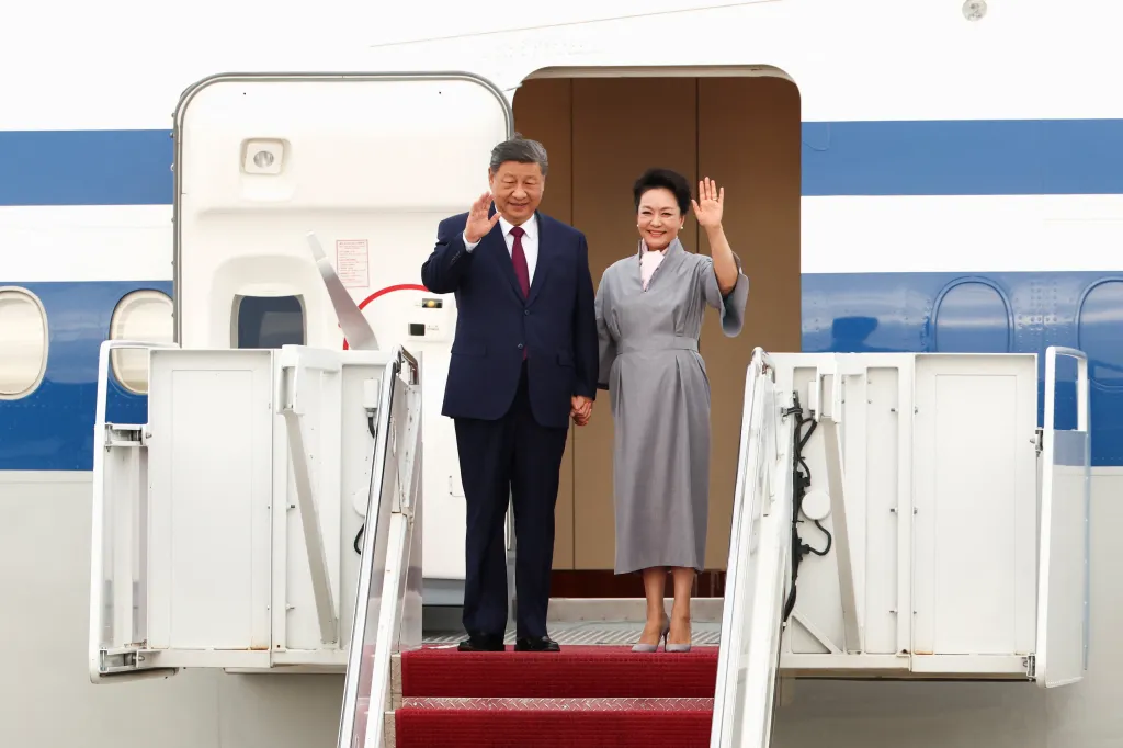 China's President Xi Jinping and his wife Peng Liyuan wave from the top of an airplane's stairs.