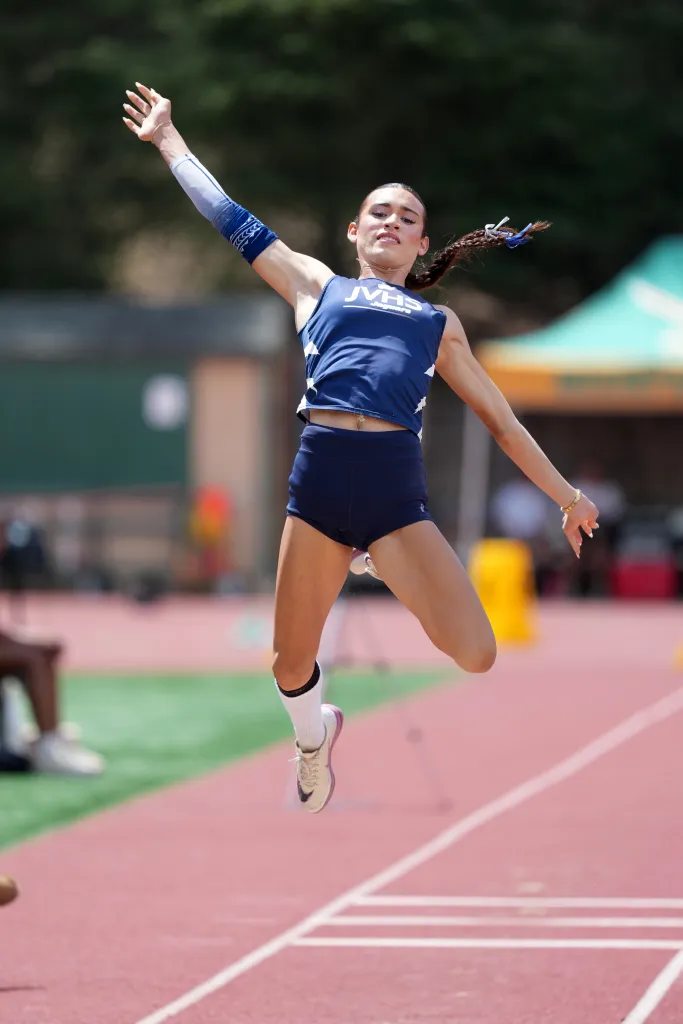 Transgender athlete AB Hernandez mid-air during the long jump event.