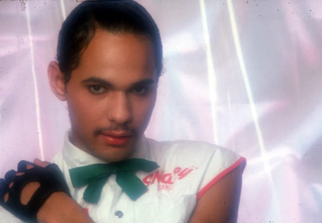 James DeBarge posing in a white shirt with a green bow tie and a fingerless glove.