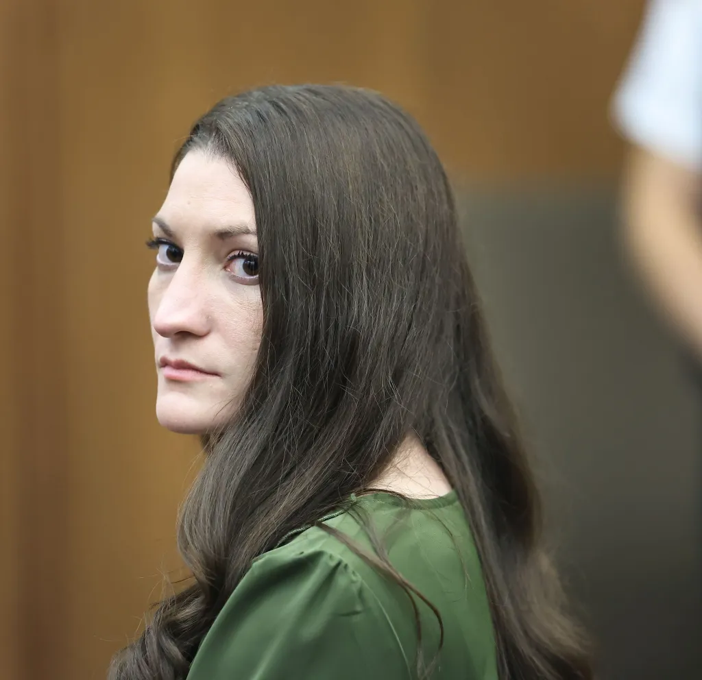 Lindsay Clancy looking over her shoulder with long brown hair and a green top, in Plymouth Superior Court.
