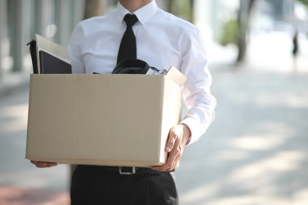 Unemployed businessperson carrying a cardboard box.