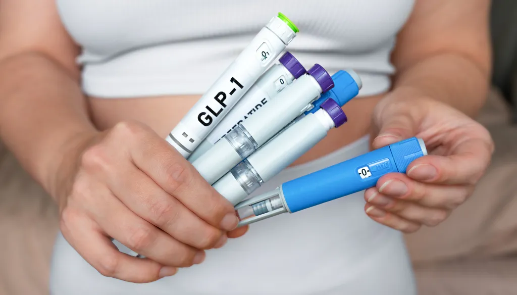 A woman holds several GLP-1 and Tirzepatide injection pens for weight loss and diabetes treatment.