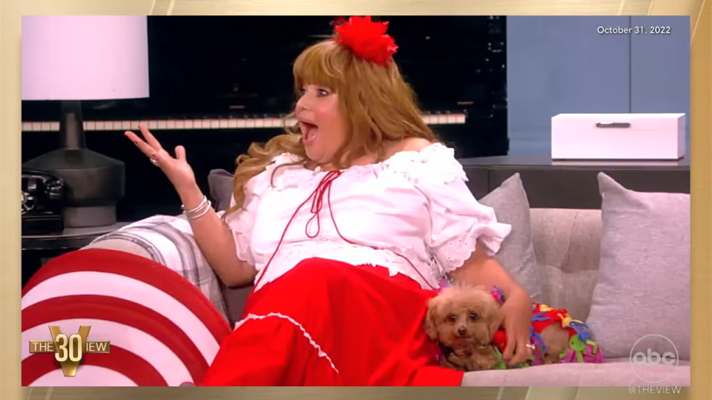 Ana Navarro-Cárdenas in a red and white costume, holding a small dog.