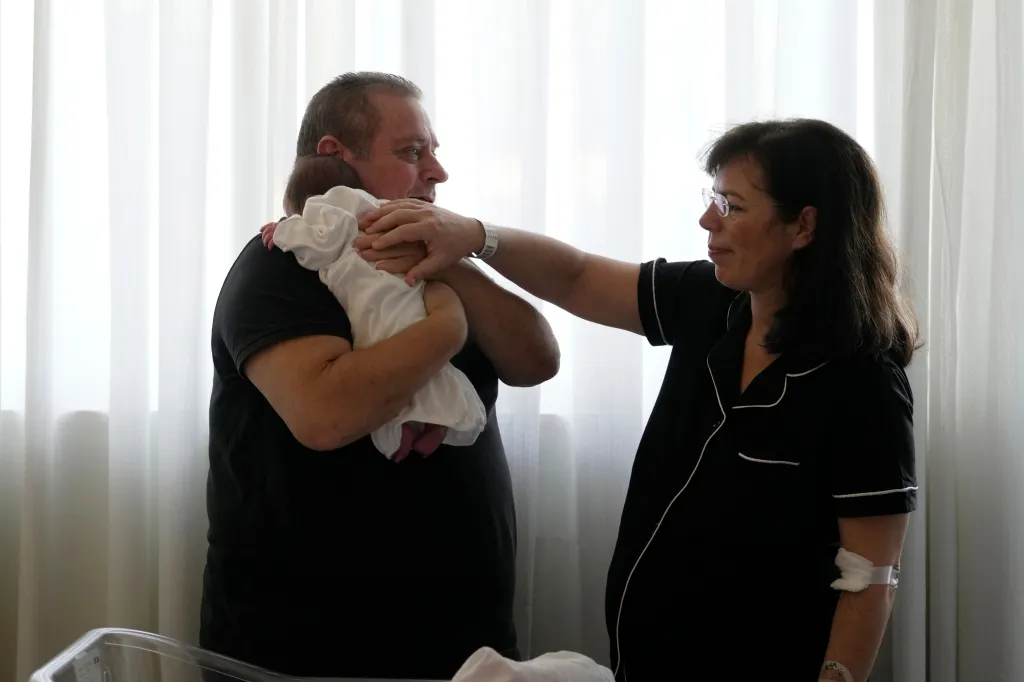 Constantinos Raptis holds his newborn daughter, Georgia, as his wife, Cristina Rapti-Tzelepi, gently touches the baby.