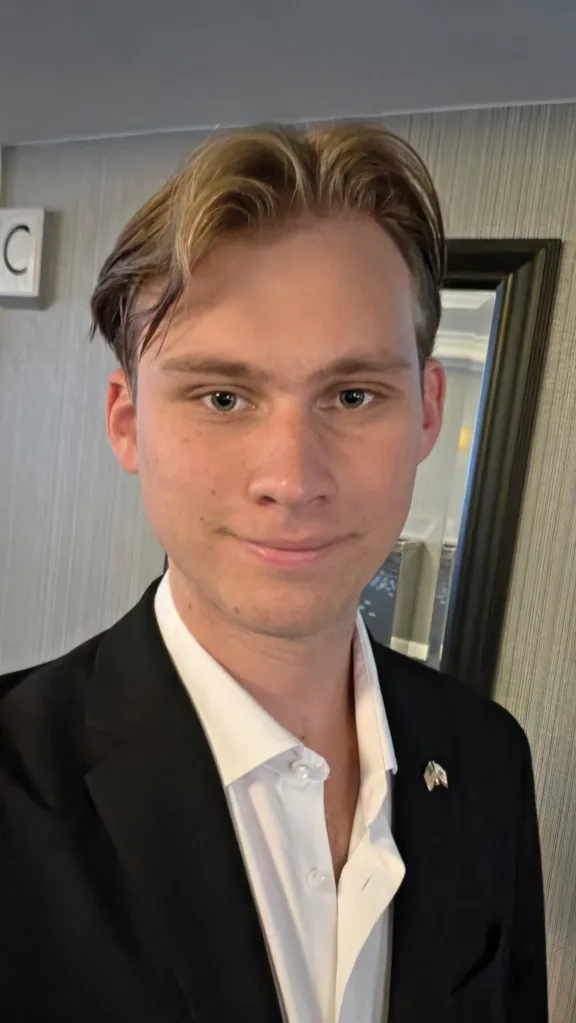 Cooper Vincik, a senior at Chapman University, wearing a suit and looking at the camera.