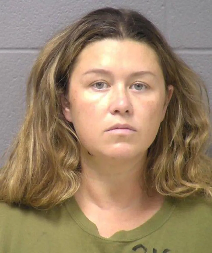 Mugshot of Corie A. Walsh, a woman with long, light brown hair, wearing a green t-shirt, looking directly at the camera.
