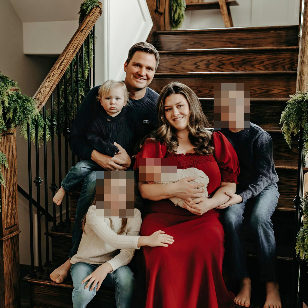 Corie Walsh and her family pose on a staircase decorated with garlands.
