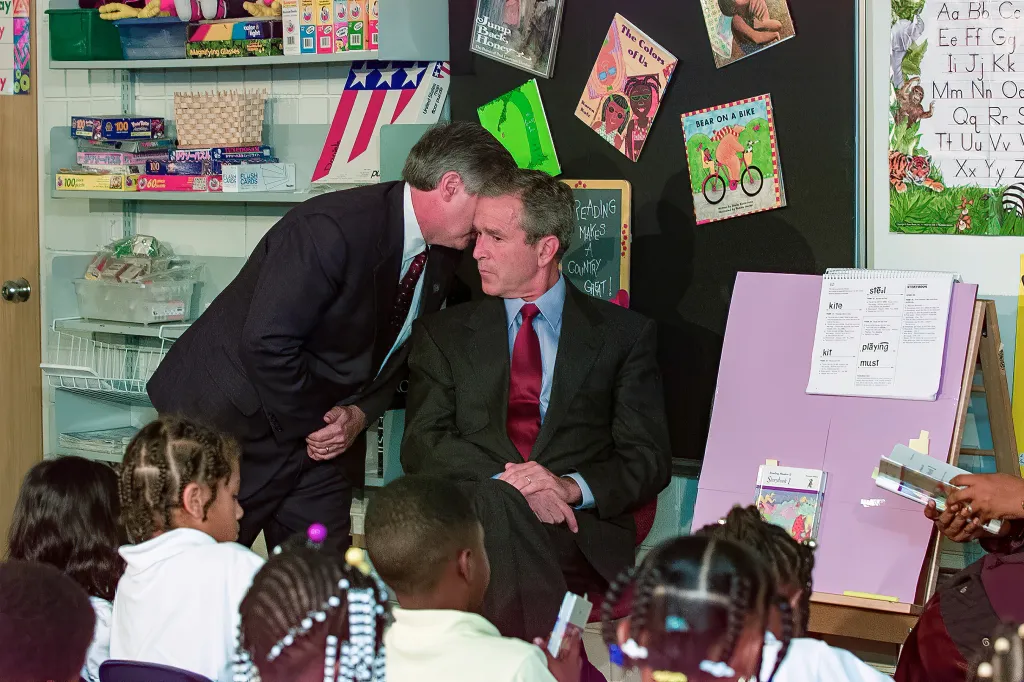 White House Chief of Staff Andrew Card whispers into President George W. Bush's ear in a classroom setting.