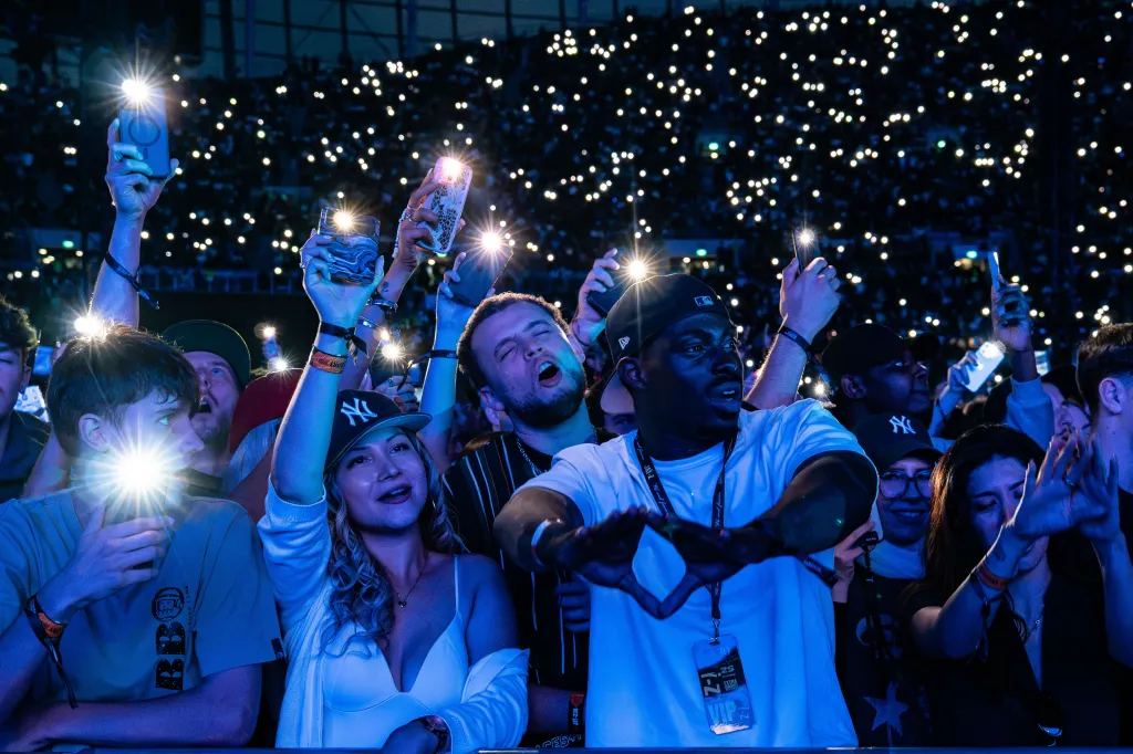 Excited fans hold up phones with flashlights on at the Jay-Z 30 concert.