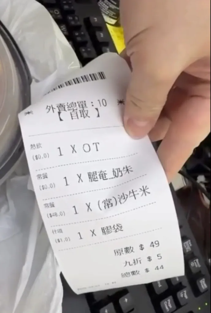 A person holding a receipt for an order including satay beef pasta.