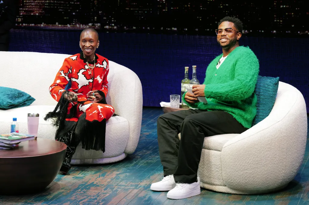 Cynthia Erivo and Kwame Onwuachi sit on chairs on a stage.