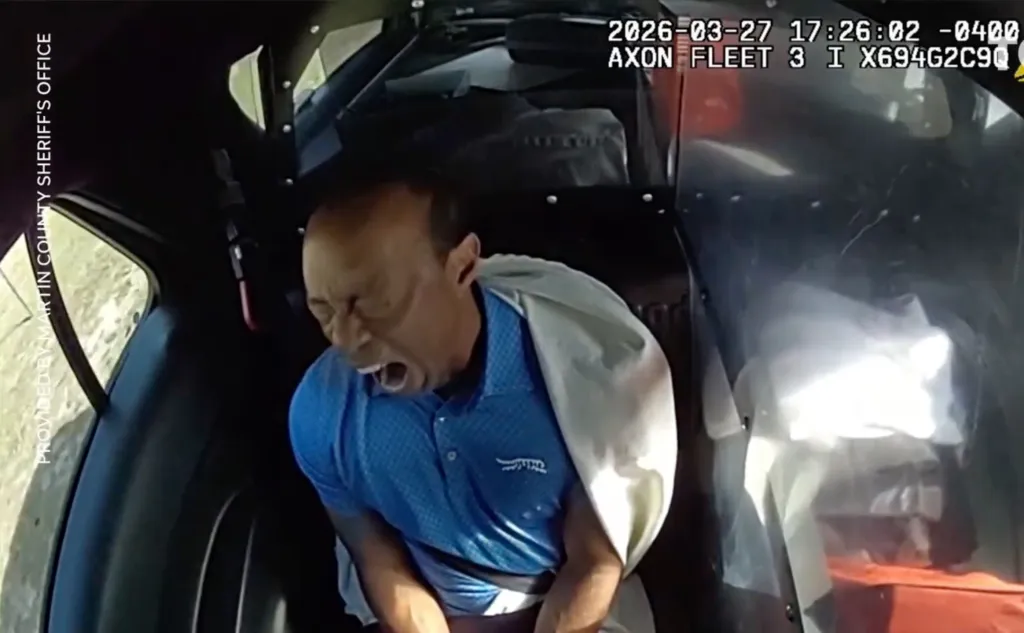 Tiger Woods in the back of a police car, appearing disoriented and distressed.