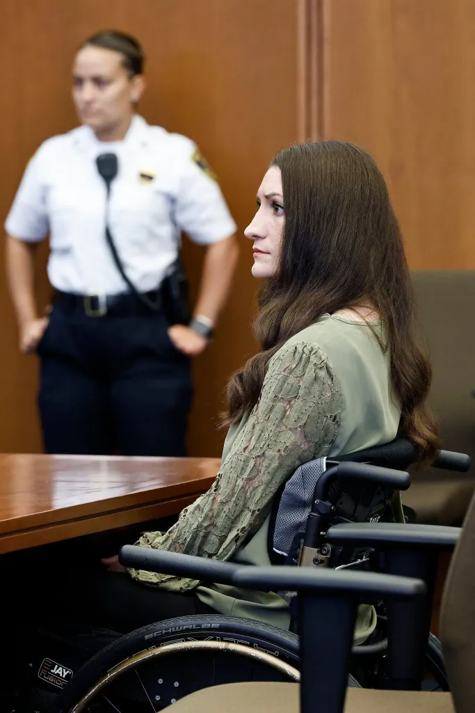 Defendant Lindsay Clancy in a wheelchair looks toward the courtroom.