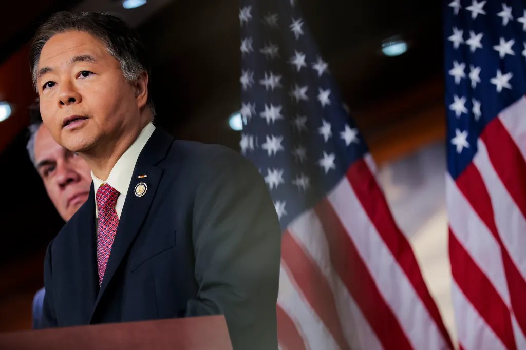 Democratic Caucus Vice Chair Ted Lieu speaks at a news conference, with US flags in the background.