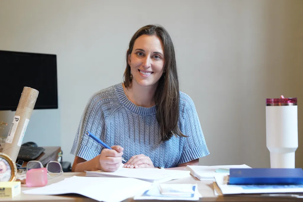 Hallie Shoffner, a Democratic U.S. Senate candidate, smiles while writing at a desk in her campaign office.