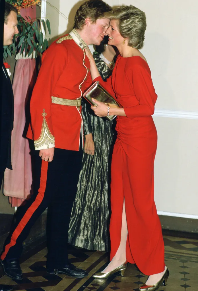 Diana, Princess of Wales, in a red dress, kisses her brother Earl Charles Spencer, in military uniform.
