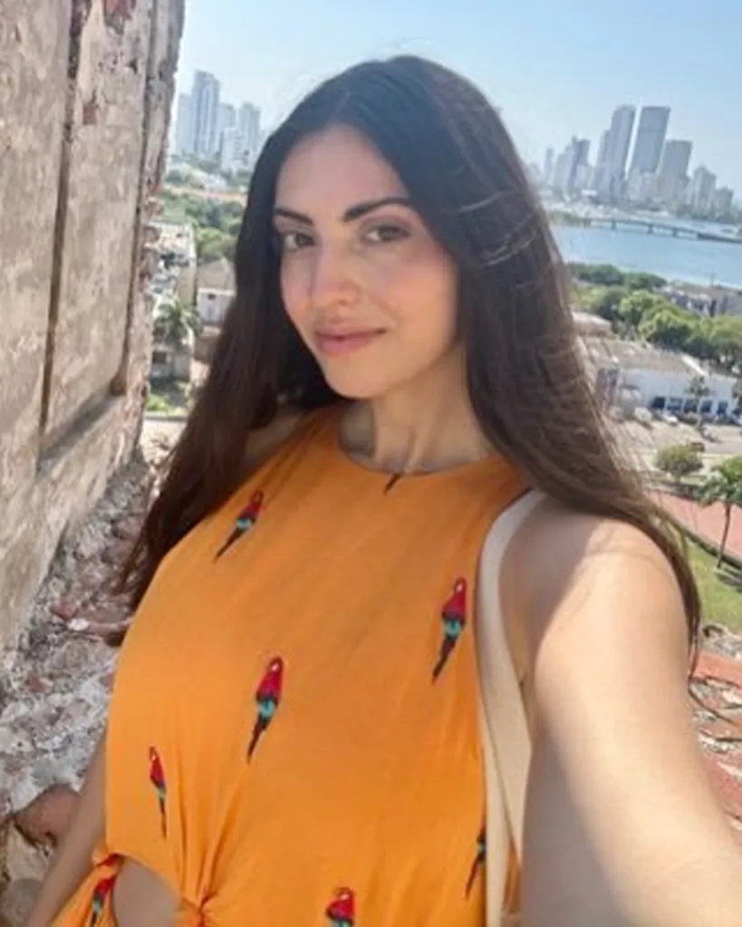 Emilia Rowland, Director of New Media and Cultural Communications at the NYC Office of the Mayor, in a selfie wearing an orange dress.