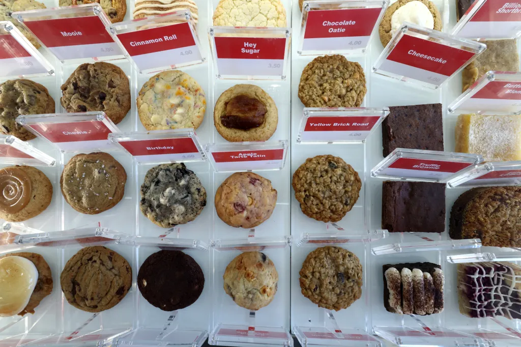 A display of various cookies and brownies with price tags from Zooies Cookies.