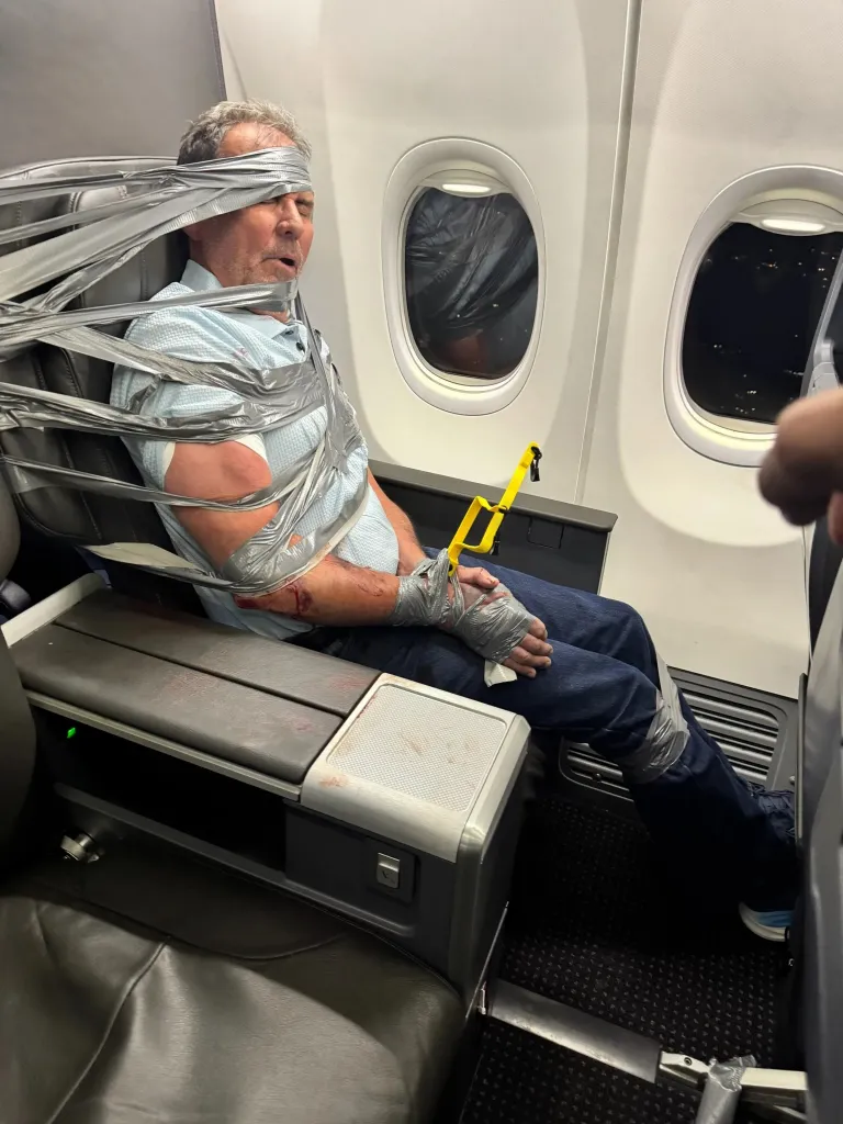 A man is duct-taped to an airplane seat.