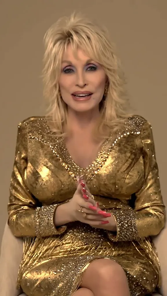 Dolly Parton wearing a gold sequined dress and speaking.