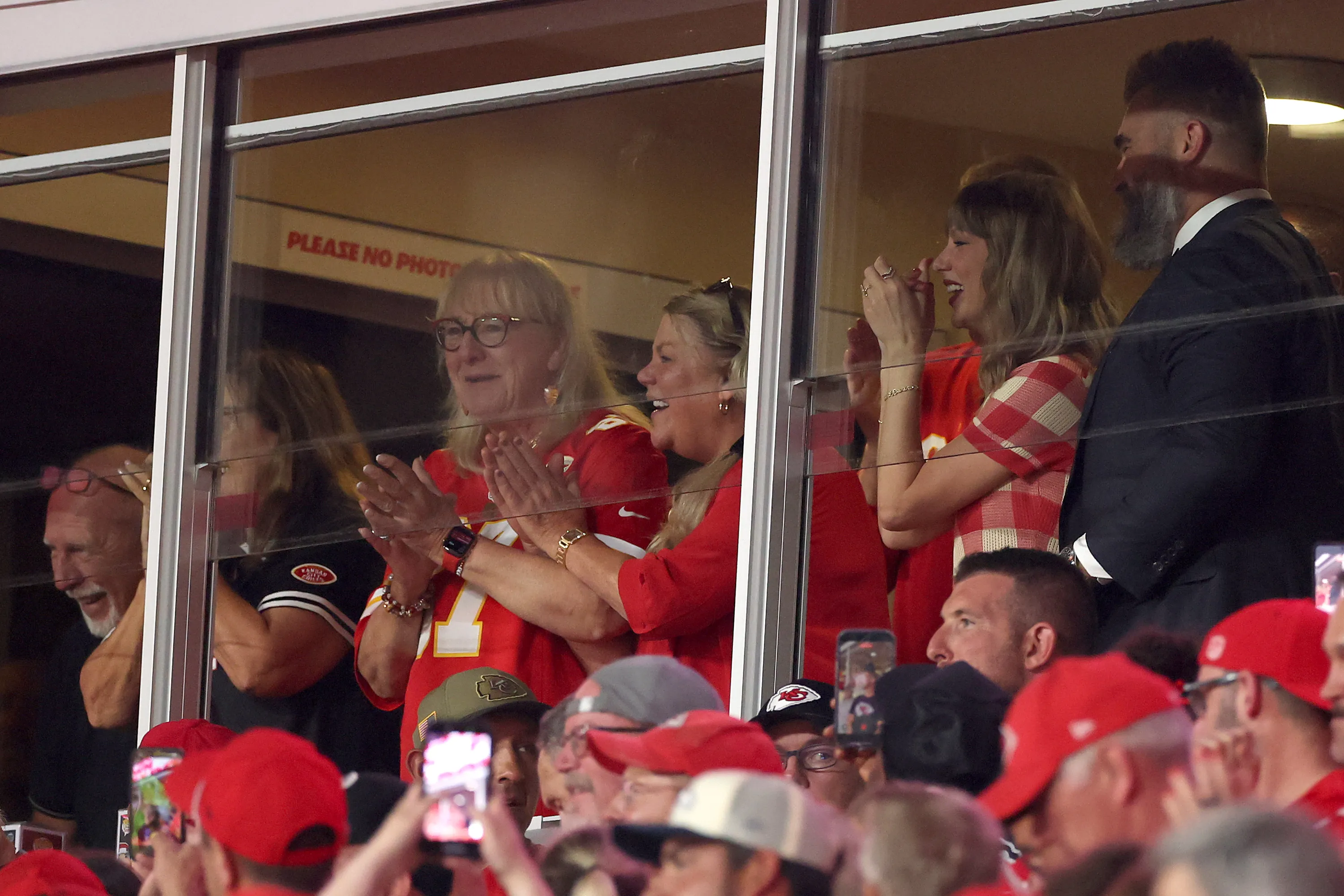 Donna Kelce, Taylor Swift, and Jason Kelce celebrating at a Kansas City Chiefs game.