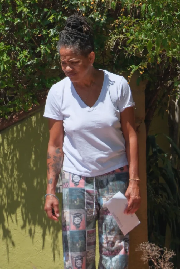 Doria Ragland holding mail while tending to her garden.