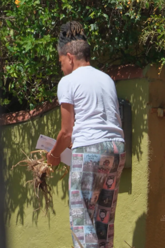 Doria Ragland retrieves mail and holds a plant while tending to her garden.