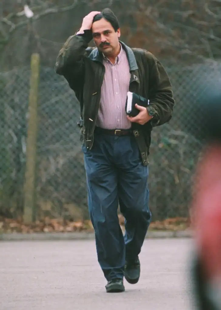 Dr. Hasnat Khan walking while holding his head and carrying a book.