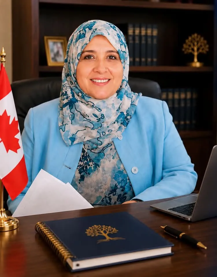 Dr. Khdiha R Metwally, mother of Abdulrahman El Bahnasawy, in a blue hijab and jacket, smiles at her desk with a Canadian flag to her left.