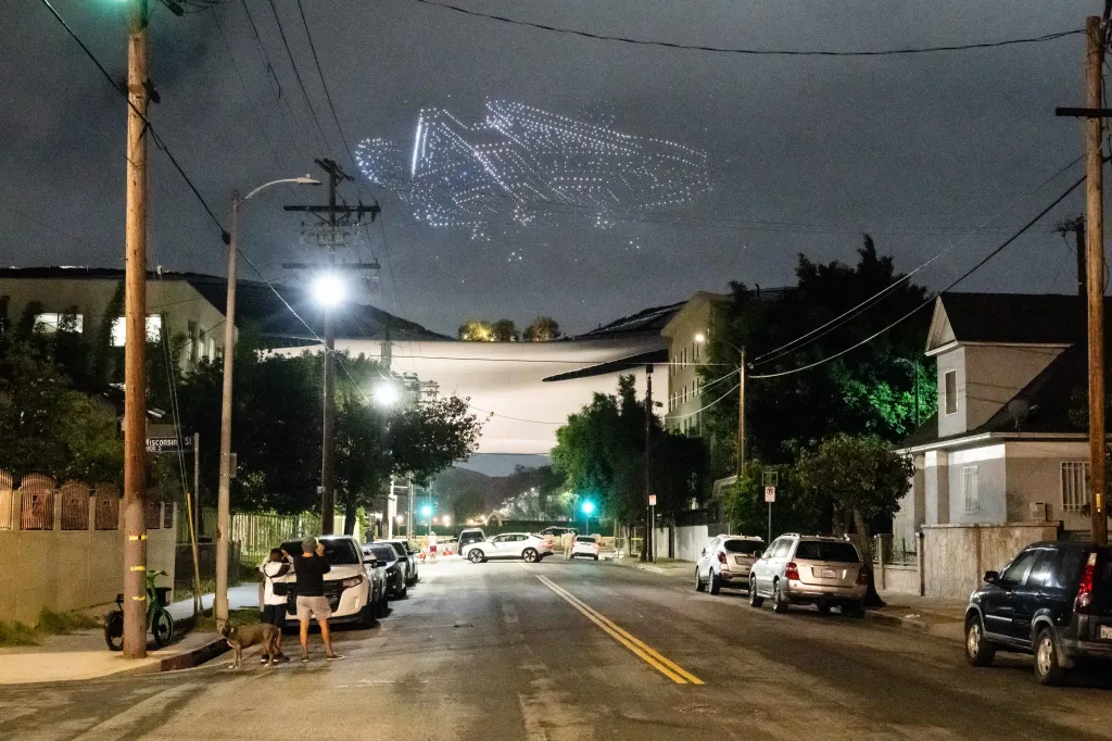 Drone show depicting a figure in the sky over a residential street at night.