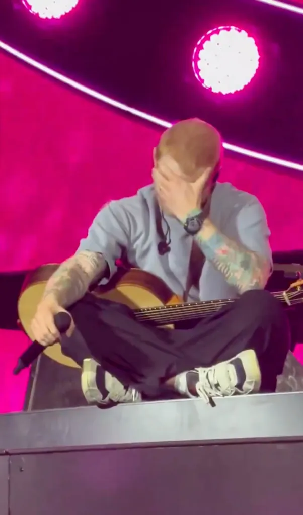 Ed Sheeran crying and holding a guitar during a concert in Philadelphia.