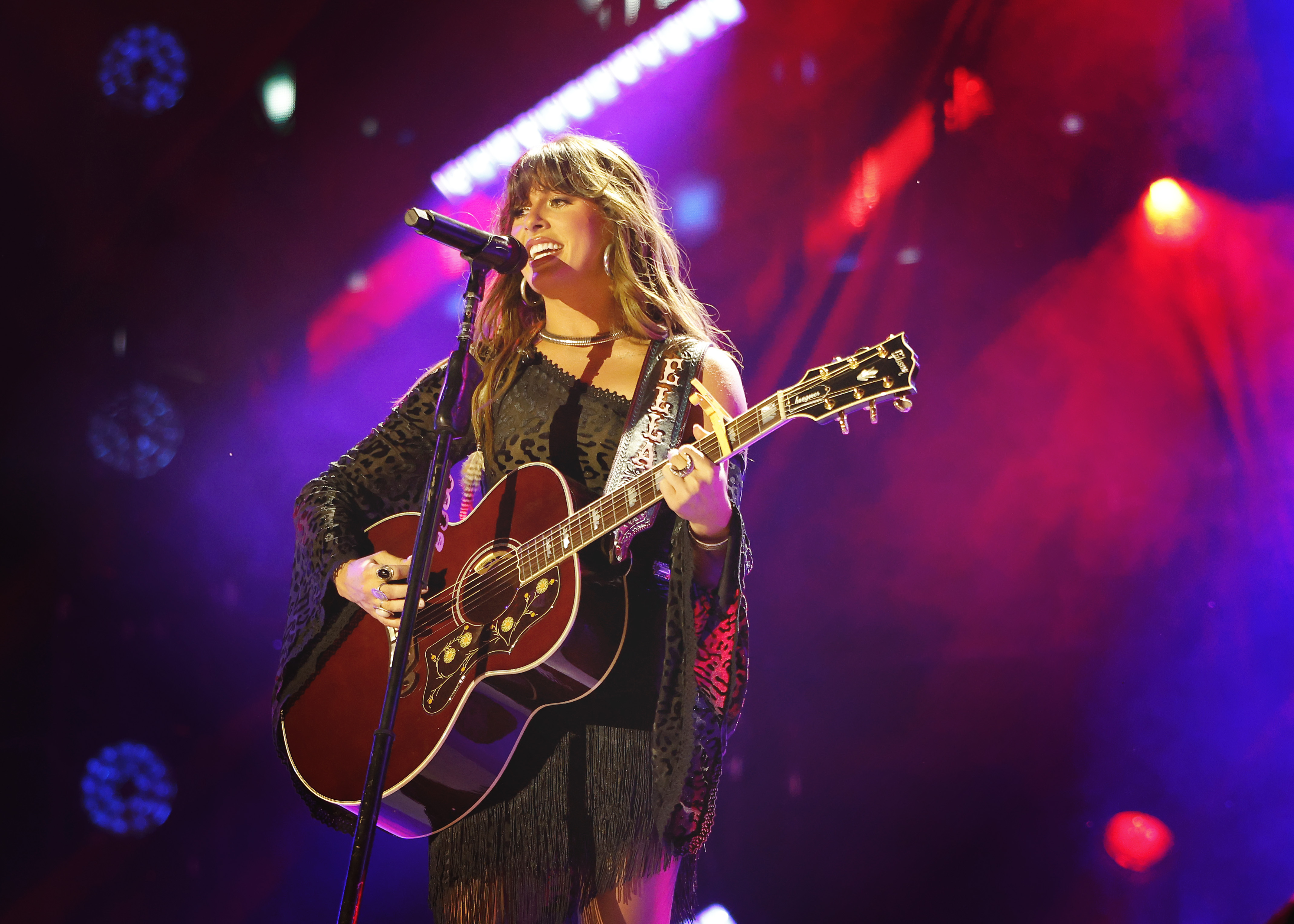 Ella Langley performing on stage with a guitar and microphone.