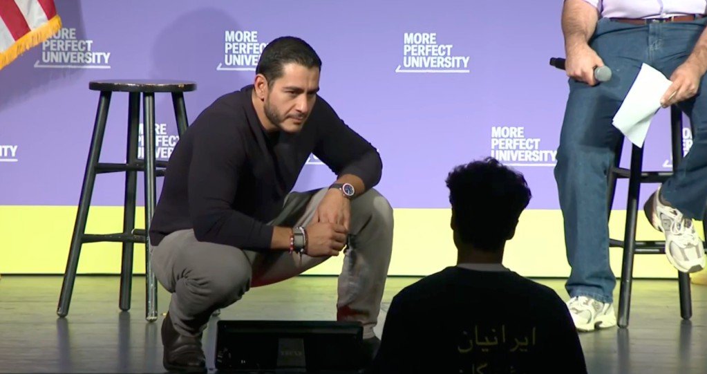 El-Sayed squats on stage addressing the audience.