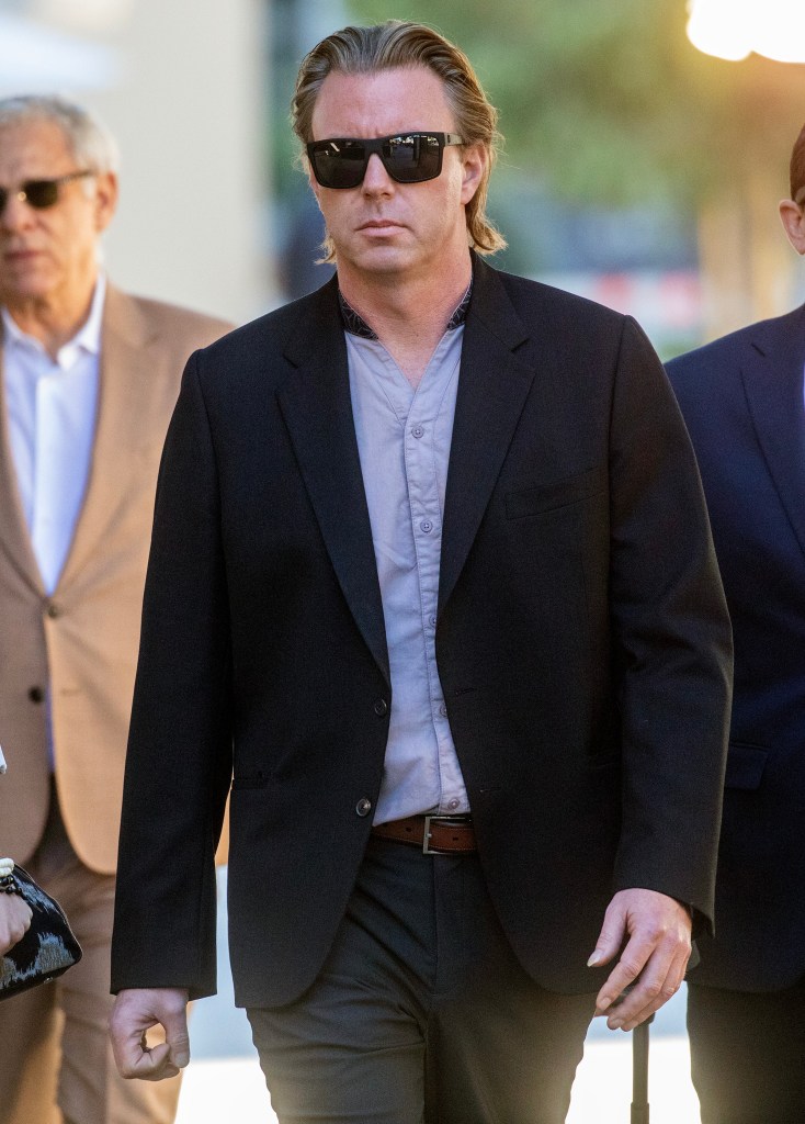 Elijah Blue Allman walks in a dark suit with sunglasses on.