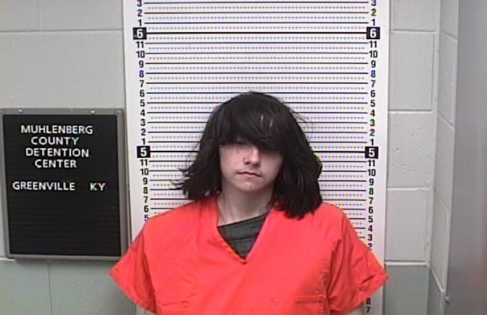 Elijah Mayes mugshot, a young person with dark hair, in an orange jumpsuit, in front of a height chart and a sign for Muhlenberg County Detention Center.