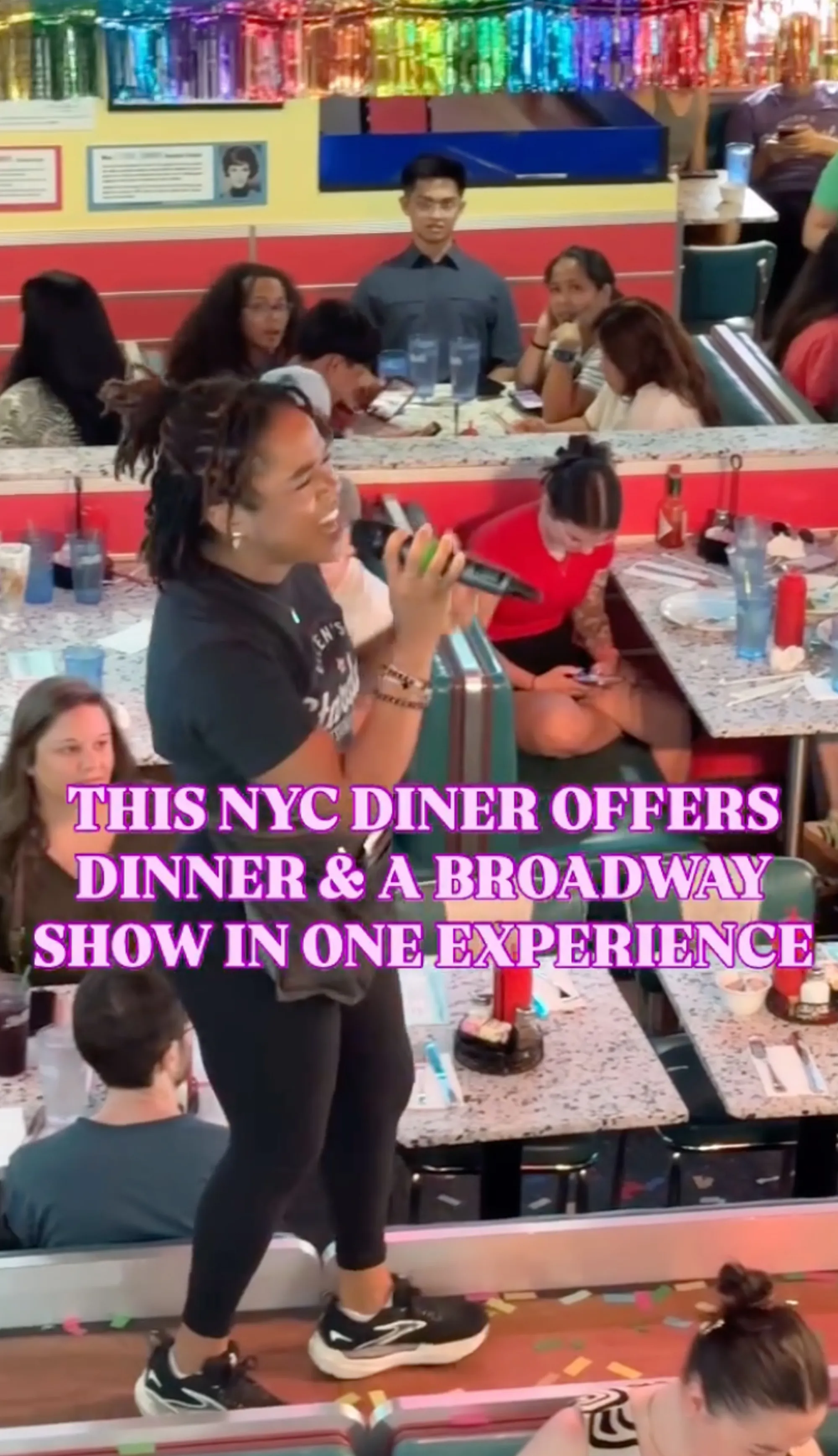 A performer sings into a microphone to a dining room full of people in a diner.