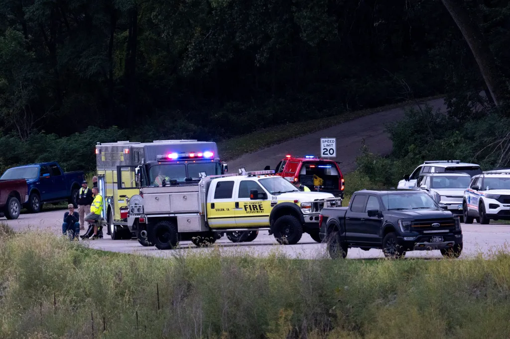 Emergency response vehicles and personnel gathered at an Iowa River boat ramp near the Lake Macbride spillway.