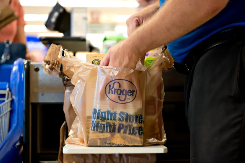 A Kroger employee bags groceries for a customer.