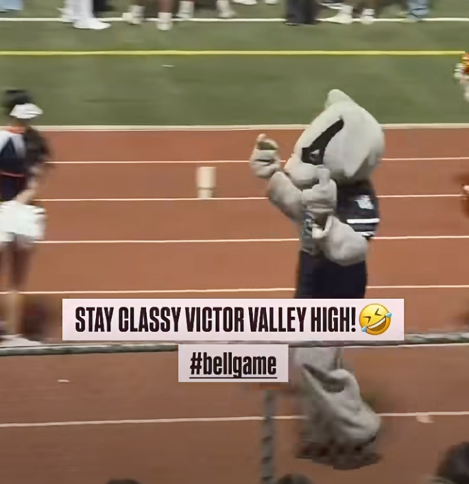 A mascot on a running track giving a middle finger.