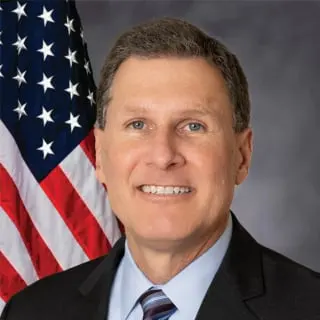 Headshot of U.S. Attorney Eric Grant smiling in front of an American flag.
