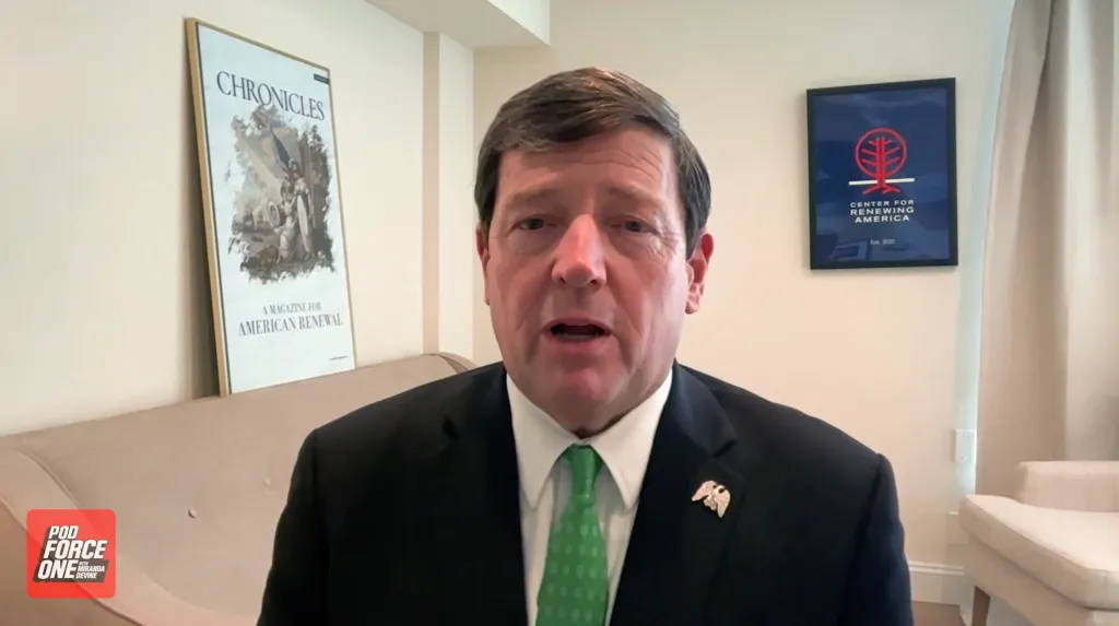 Ed Martin, wearing a black suit and green tie, speaks during an interview on Pod Force One.