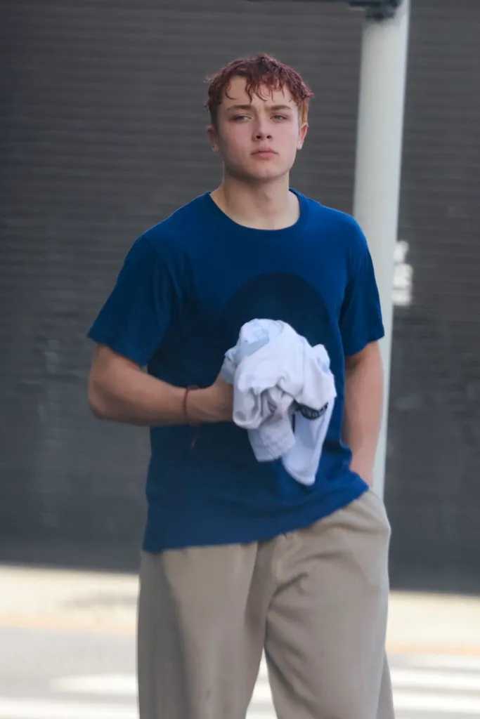 Knox Jolie-Pitt in a blue T-shirt and tan pants, holding a white towel after Muay Thai class.