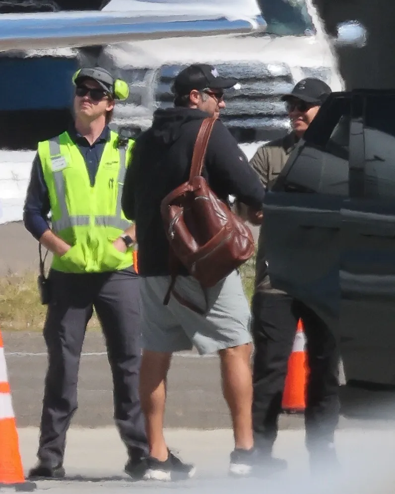 Lady Gaga's fiancé Michael Polansky with a brown leather bag, standing with two men.