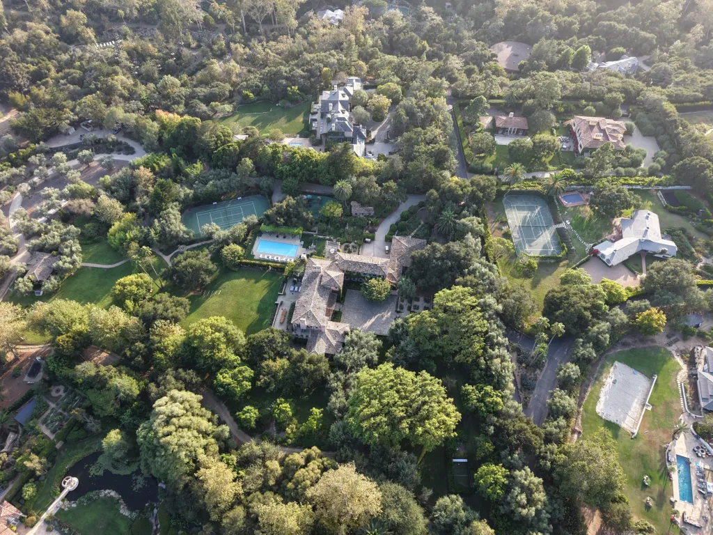 Aerial view of Prince Harry and Meghan Markle’s expansive Montecito estate, surrounded by lush greenery, manicured grounds, a tennis court, and a swimming pool in California.