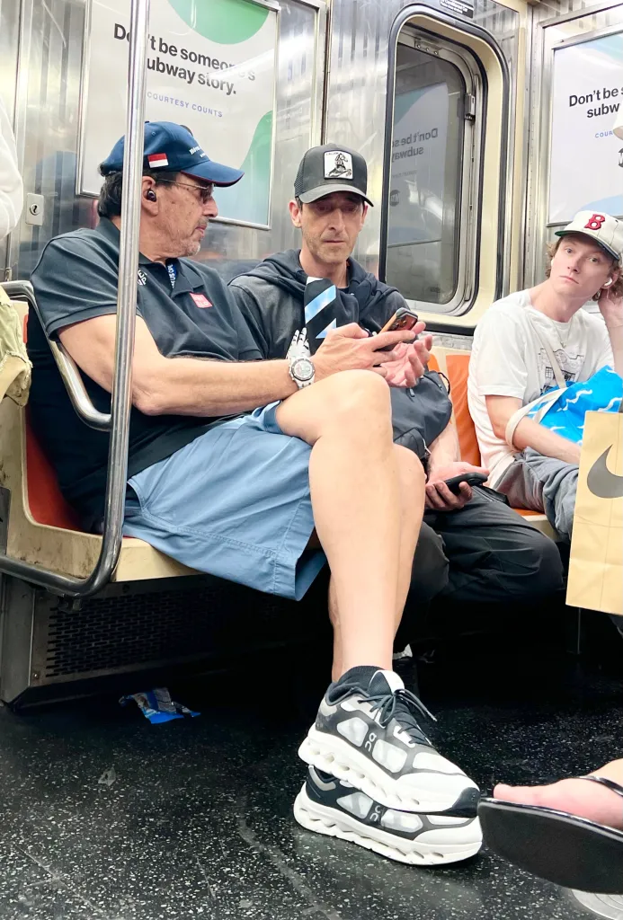 Adrien Brody and a friend riding the New York City subway.