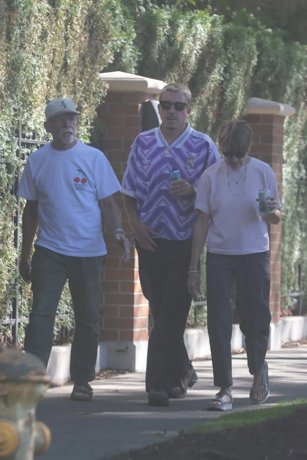 Macklemore walking with his parents, wearing a purple Real Madrid t-shirt and sunglasses.