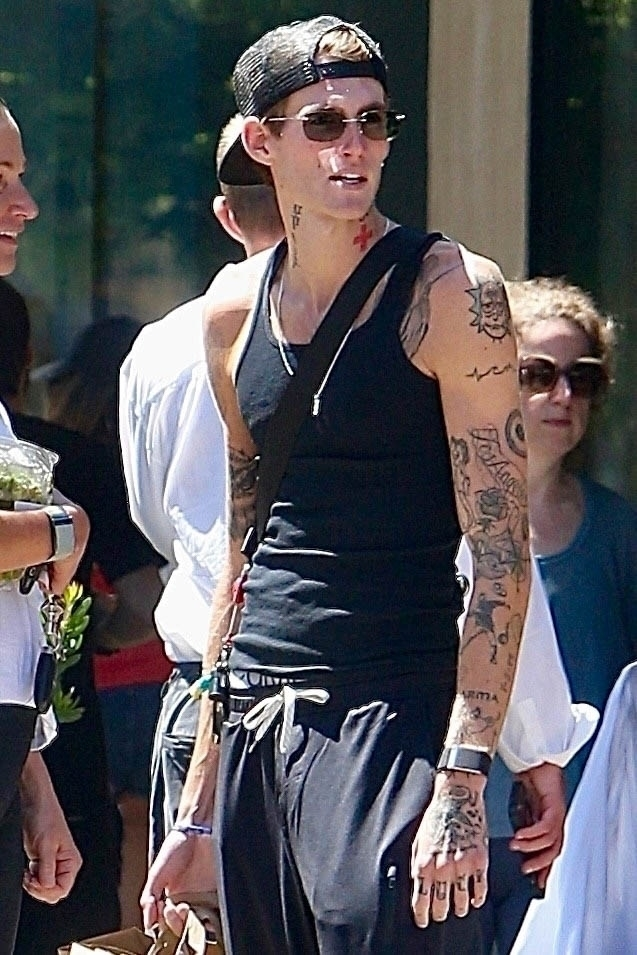 Presley Gerber, wearing a black tank top and backward cap, shows off his many tattoos while shopping.
